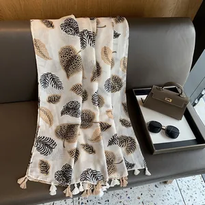 Detail of thin cotton linen scarf with leopard maple leaf patterns and tassel edges