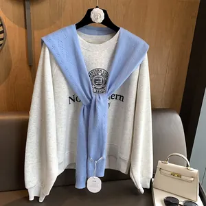 Detail of light blue knit shawl with hollow pattern paired with grey college sweatshirt