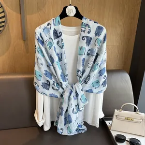 Detail of light cotton-linen scarf with blue cartoon cat prints on white shirt