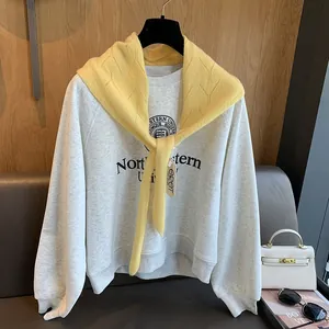 Détail d'un châle en laine tricotée jaune noué sur un sweat-shirt gris de style collège