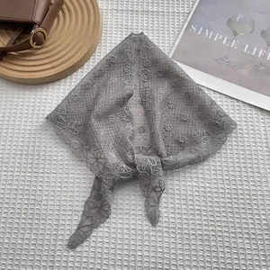 Detailed macro view of gray lace triangle kerchief with floral embroidery on white fabric