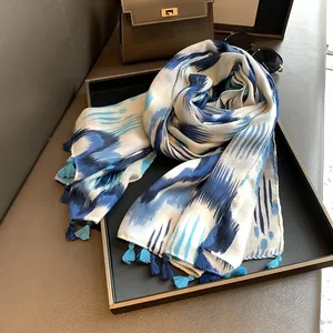 Detail of thin cotton linen scarf featuring blue tie-dye stripes and handmade tassels