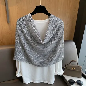 Detail of a black and white striped knit shawl with gold sequins layered over a white shirt