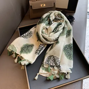 Detail of thin cotton linen scarf with green maple leaf print and fringe tassels