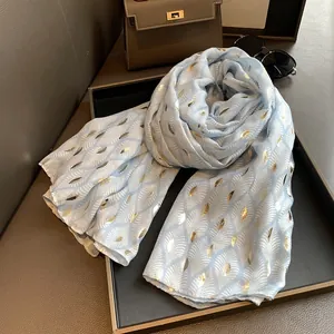 Detail van een lichtblauwe katoen-linnen sjaal met goudkleurige verendessins en lovertjes