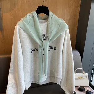 Gros plan sur le châle en tricot vert menthe avec un motif texturé en V distinct