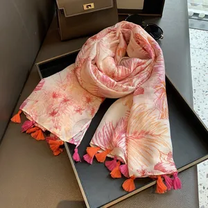 Detail of floral printed scarf with woven tassels on a tray with fashion accessories