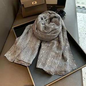 Close-up of lightweight black and white striped scarf with elegant gold foil accents