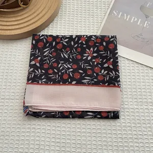 Détail d'un foulard en coton à fleurs bleu marine avec bordure rose sur tissu gaufré