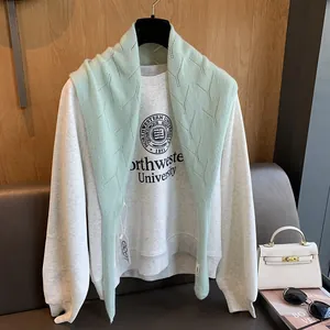 Détail d'un châle en laine vert menthe ajouré avec un sweat-shirt universitaire