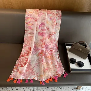Detail of tropical monstera leaf print scarf with vibrant pink and orange fringe tassels