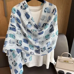 Close-up of cotton linen scarf featuring blue cartoon cat prints and soft fabric texture
