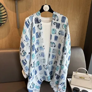 Detail of light blue cotton linen scarf featuring a cute cartoon cat print over a white tee