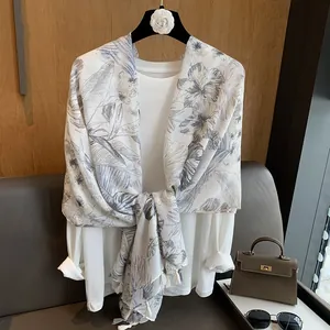 Detailed view of floral cotton linen scarf with elegant tassels on a white casual top