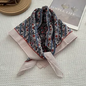Détail d'un foulard carré en coton rose avec rayures bleu marine et motifs cerises
