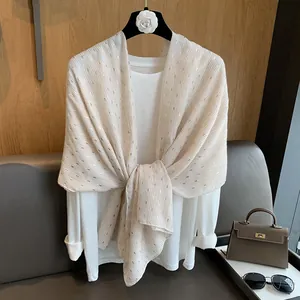 Close-up of white semi-transparent scarf with gold sequins styled over a white blouse