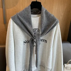Détail d'un châle en laine grise sur un sweat-shirt de style universitaire de couleur crème