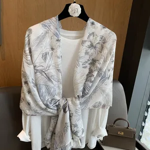 Detail of floral palm leaf print scarf with tassels on a wooden interior background