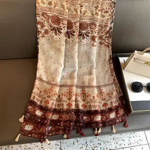 Dettaglio della sciarpa floreale bohémien con eleganti frange su un divano in pelle