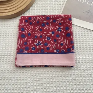 Détail d'un foulard en soie rouge foncé à motif baies et bordure rose contrastée