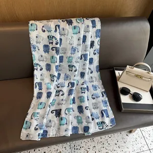 Detail of white cotton linen scarf featuring blue cartoon cat prints on leather sofa