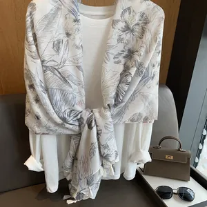 Detail of white scarf with soft floral prints and delicate fringe tassels decoration