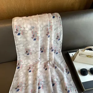 Detail view of cotton linen scarf with red berry print draped on a leather sofa