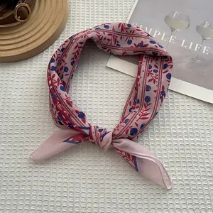 Gros plan d'un foulard rose avec motif de feuilles rouges sur fond texturé blanc