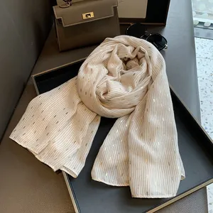 Detail of light beige scarf featuring elegant golden foil patterns and pleated texture