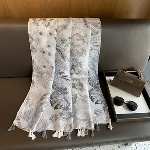 Detail of tropical plant print on a cotton-linen scarf with fine tassel fringe decor