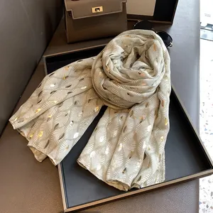 Detail van saliegroene sjaal met goudkleurige bladprint op chiffon materiaal