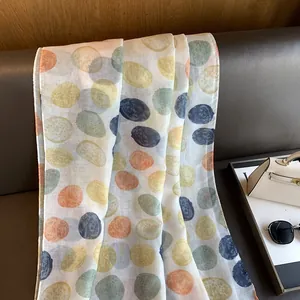 Detail of artistic watercolor polka dot scarf draped over a brown leather sofa
