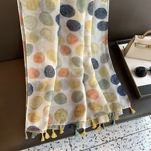 Detailed close-up of a linen cotton scarf featuring colorful dots and fringe tassels