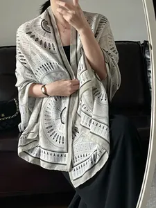 Detail of bohemian geometric print on lightweight long scarf draped over black dress