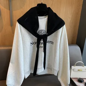 Détail du châle en laine à losanges assorti à un sweat-shirt avec imprimé collège