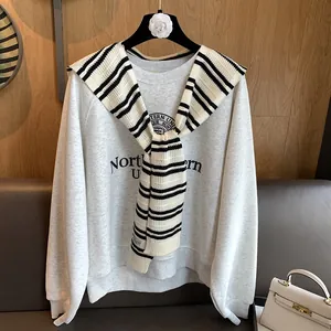 Detail of a casual grey sweatshirt styled with a black and white striped knit shawl wrap