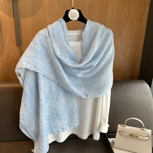 Light blue striped scarf with gold foil accents draped over a white long-sleeve top