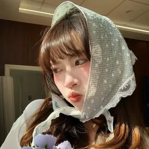 Dettaglio del foulard a triangolo floreale verde chiaro con pizzo bianco e laccetti