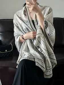 Close-up of lightweight shawl with brown tribal geometric patterns on beige fabric
