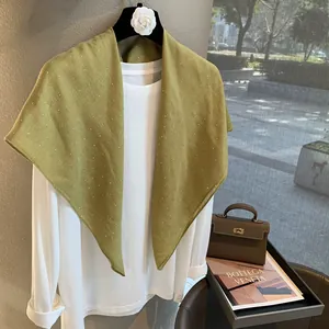 Foulard triangulaire en lin vert olive avec paillettes sur un t-shirt blanc