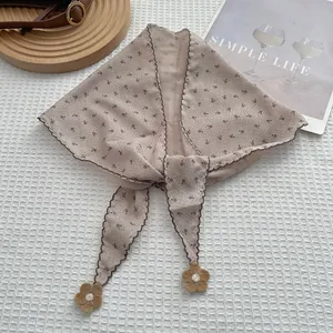 Floral triangle headscarf with scalloped edges and crochet flower charms on white fabric