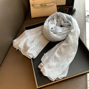 Close-up of blue and white striped scarf with gold foil accents on a luxury display