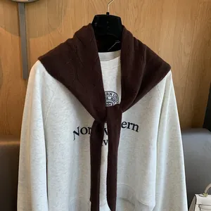Détail d'un châle en tricot à losanges marron sur un sweat-shirt gris académique