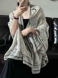 Macro detail of a lightweight tribal print shawl with black ethnic patterns on beige fabric