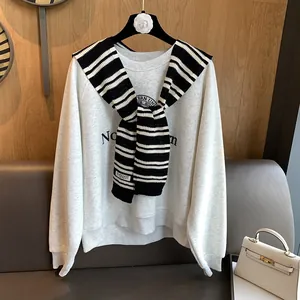 Detail showing high-quality black and white striped knit shawl layered over a gray sweatshirt