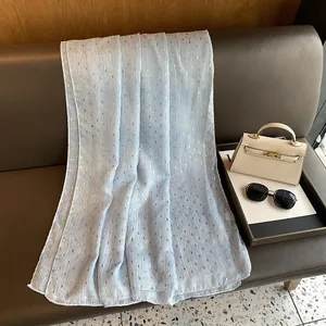 Detail of light blue pleated cotton linen scarf with gold foil dots on a leather sofa