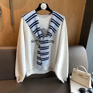 Detail of blue and white striped knit shawl styled over a cream sweatshirt in a cozy scene