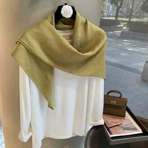 Écharpe en lin vert olive ornée de strass brillants disposée sur un cintre élégant
