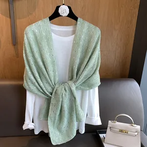 Detail showing pale green cotton linen scarf with vertical stripes and shimmering sequins