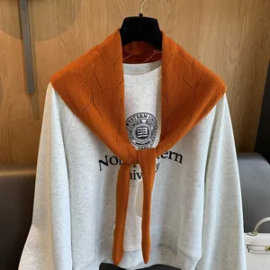 Détail d'un châle en laine orange brûlé sur un sweat-shirt universitaire gris chiné